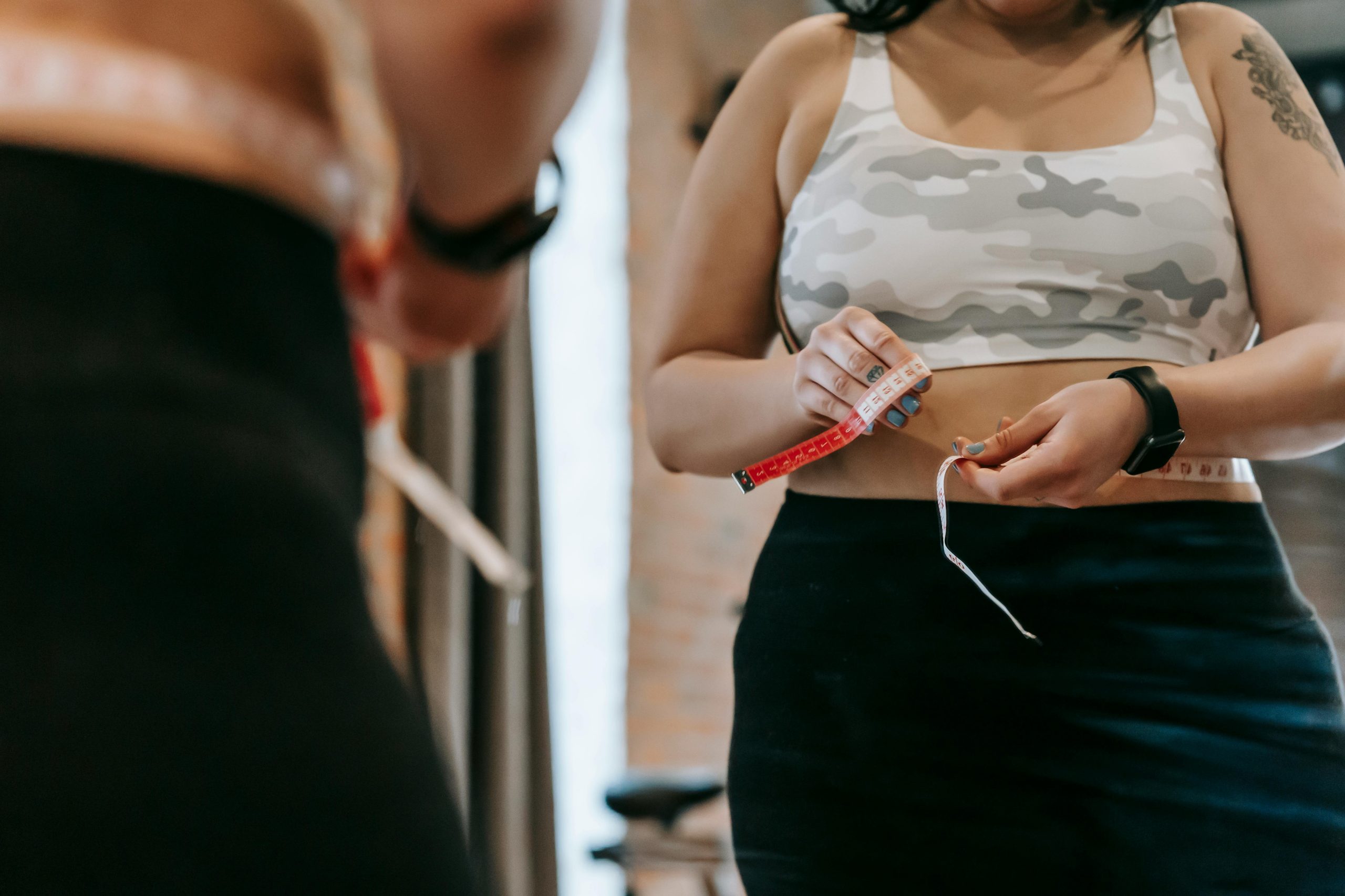 Woman measuring her waist in the mirror